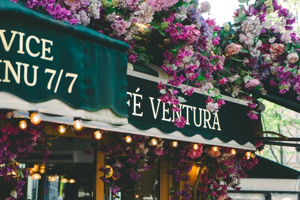 Terrasse de café décorée de fleurs en façade – charme authentique en centre-ville.